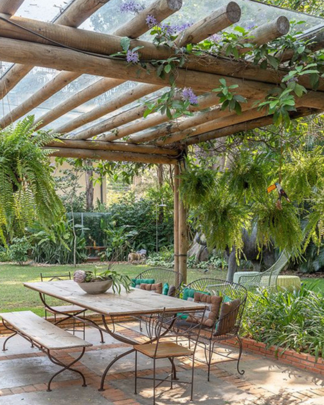 Aménagement terrasse avec une pergola en rondins de bois avec une table en bois et métal en dessous.