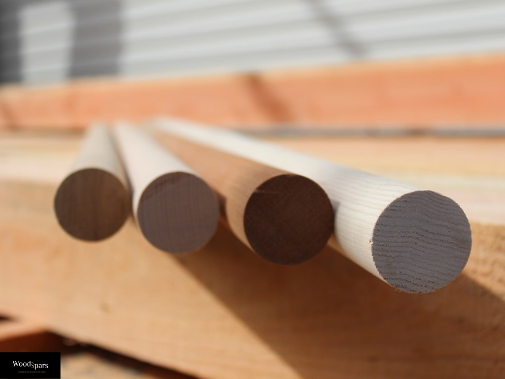 Comparaison de quatre essences de bois pour main courante ronde : chêne, hêtre, frêne et bois exotique, montrant les différentes teintes et grains.