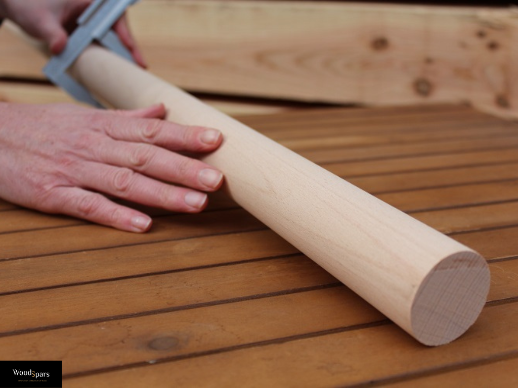 Contrôle qualité du diamètre d'une main courante ronde en hêtre massif à l'aide d'un pied à coulisse dans l'atelier Woodspars.