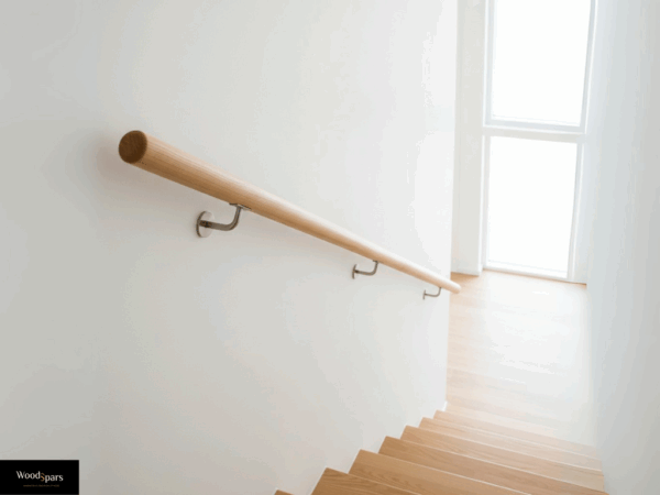 Main courante ronde en hêtre clair sur mesure, posée avec des supports en inox dans un escalier moderne et lumineux.