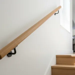 Main courante ronde en chêne massif installée le long d'un escalier en bois dans un intérieur résidentiel lumineux.