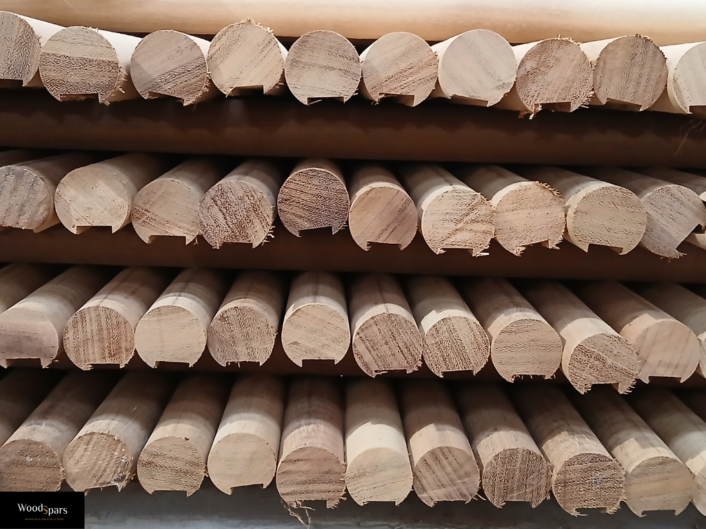 Stock de profils de mains courantes en bois massif brut dans l'atelier de fabrication Woodspars, prêts pour des projets sur mesure.