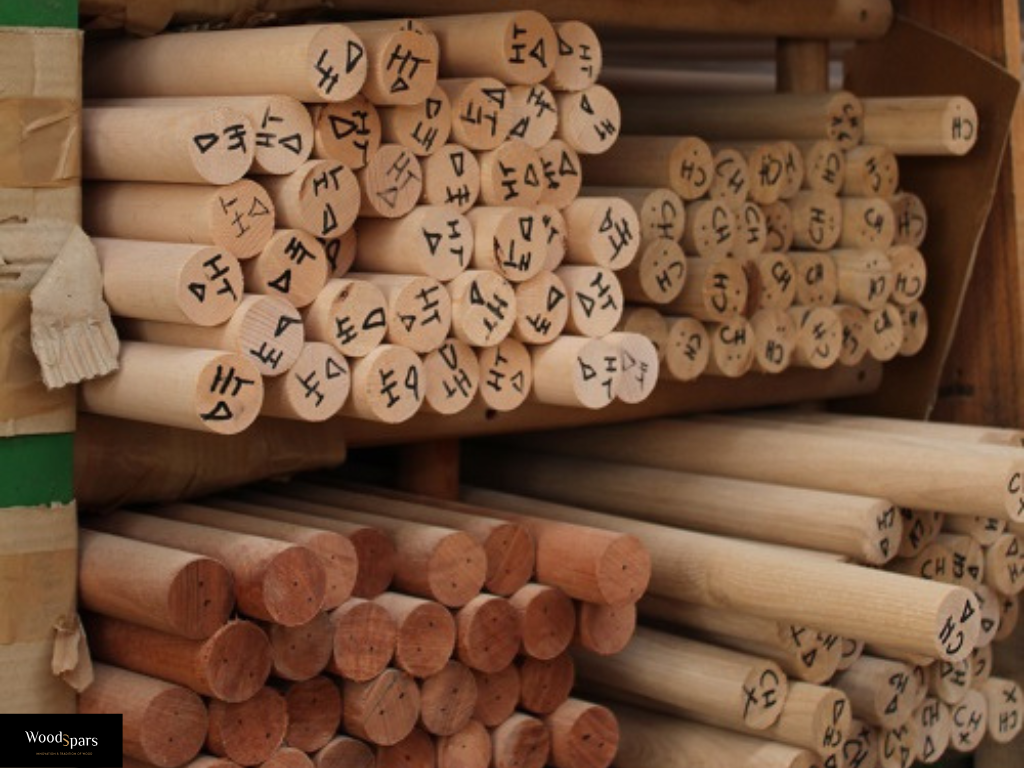 Stock de mains courantes rondes en bois brut dans l'atelier Woodspars, triées par essences (Chêne, Hêtre) et prêtes à être expédiées.
