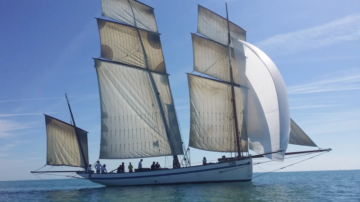 La Granvillaise, bisquine toutes voiles dehors incluant un spinnaker blanc, naviguant par beau temps en mer