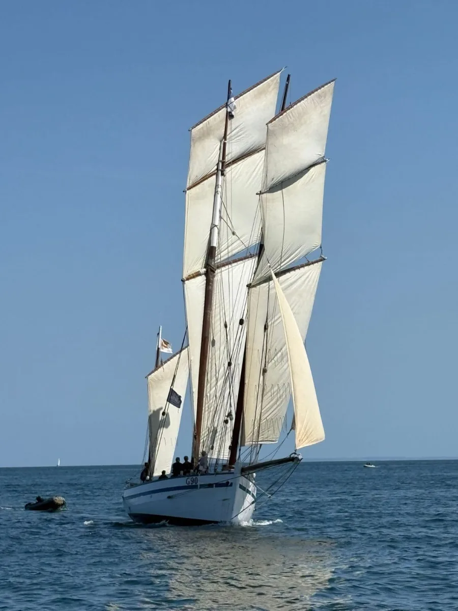 La Granvillaise, bisquine à gréement traditionnel, naviguant toutes voiles dehors en mer sous ciel bleu